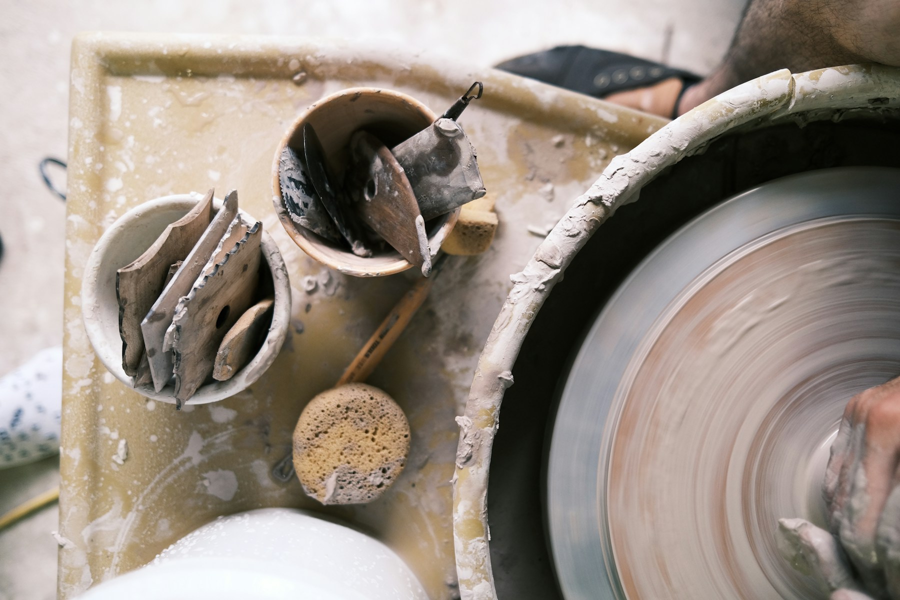 An artisan shaping a clay pot on a pottery wheel